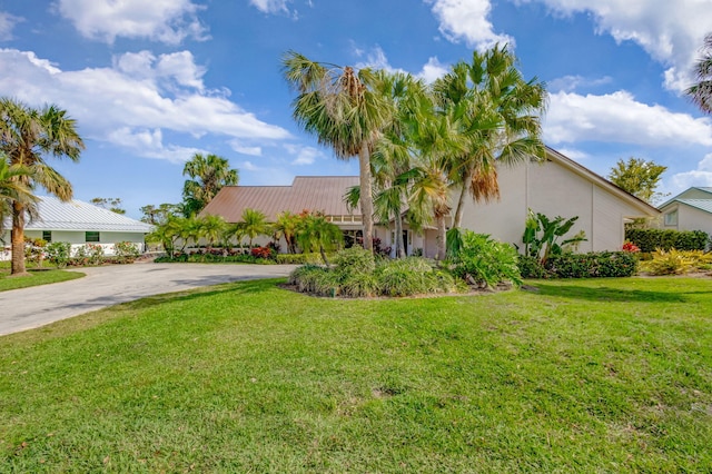 view of front of property with driveway, metal roof, and a front lawn