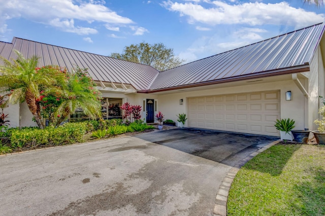 view of front of property with an attached garage, aphalt driveway, metal roof, and stucco siding