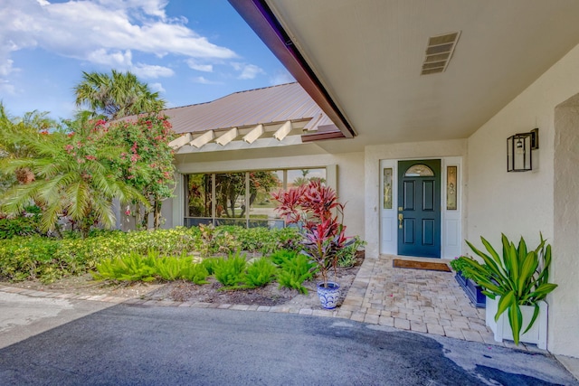 entrance to property featuring visible vents and stucco siding