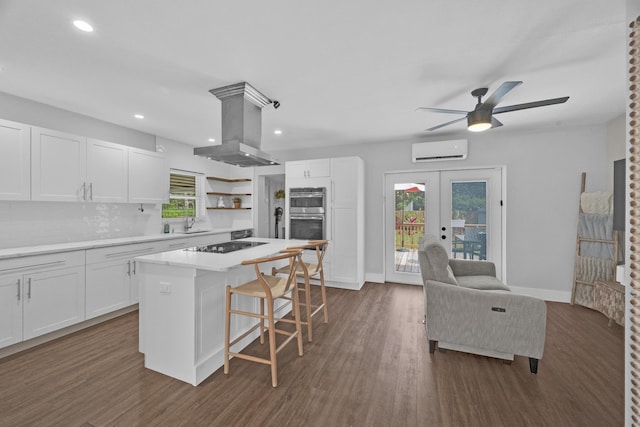 806 S 12th St, Fort Pierce, FL 34950 - kitchen featuring island range hood, white cabinetry, light countertops, and a wall mounted air conditioner