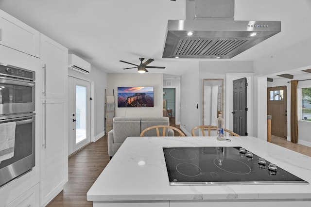 806 S 12th St, Fort Pierce, FL 34950 - kitchen featuring light stone counters, a wall mounted air conditioner, black electric stovetop, stainless steel double oven, and white cabinetry