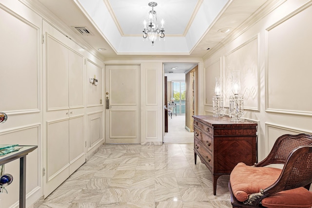 hallway with visible vents, a notable chandelier, ornamental molding, a tray ceiling, and a decorative wall