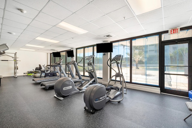 exercise room featuring visible vents, a paneled ceiling, and baseboards