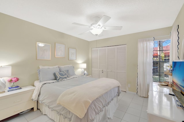 bedroom with ceiling fan, a textured ceiling, a closet, and light tile patterned flooring