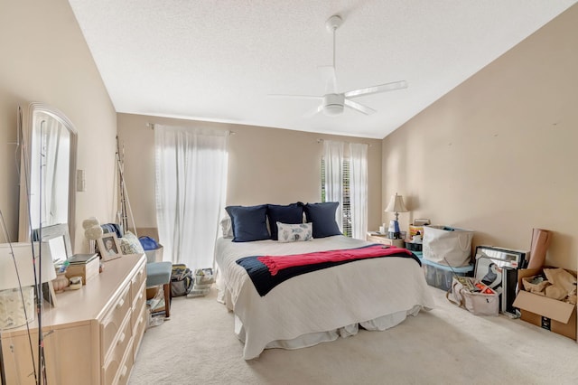 bedroom with lofted ceiling, ceiling fan, a textured ceiling, and light carpet