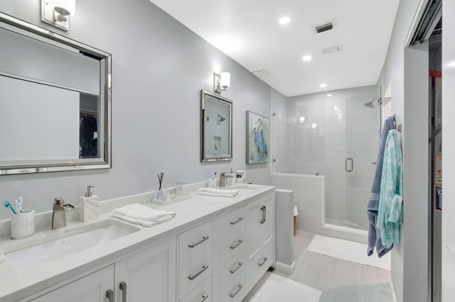 bathroom featuring double vanity, a shower stall, visible vents, and a sink