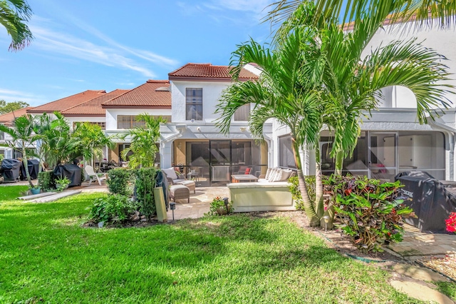 back of property featuring a patio, a lawn, a sunroom, and a tiled roof