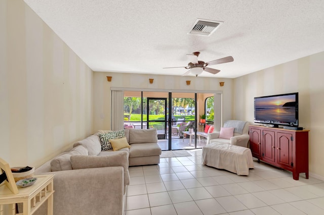 living room with light tile patterned floors, visible vents, a textured ceiling, and a ceiling fan