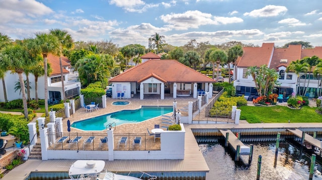 pool with a patio, a dock, a community hot tub, and fence