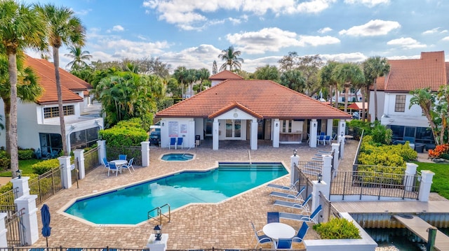 community pool featuring a community hot tub, a patio area, and fence