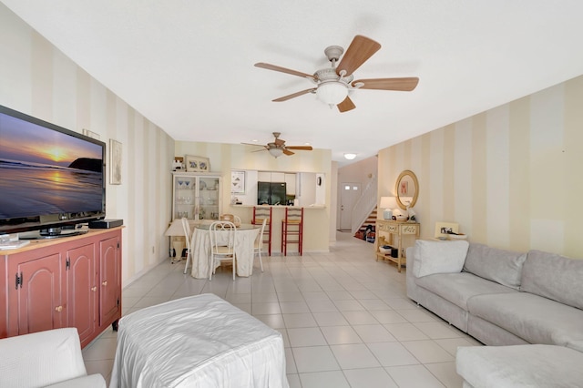 living room featuring stairs, ceiling fan, light tile patterned flooring, and wallpapered walls