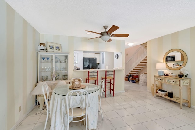 dining space with light tile patterned floors, ceiling fan, stairway, and a textured ceiling