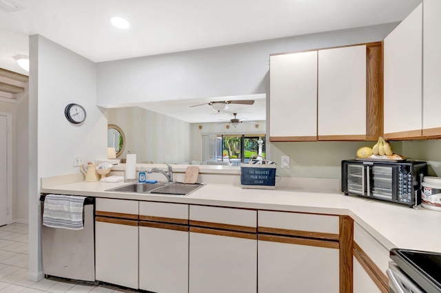 kitchen with a toaster, light countertops, stainless steel dishwasher, white cabinetry, and a sink