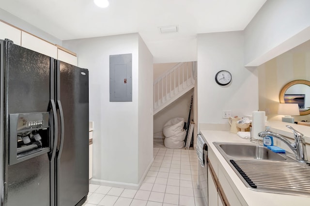 kitchen featuring light tile patterned flooring, black fridge with ice dispenser, white cabinets, light countertops, and electric panel