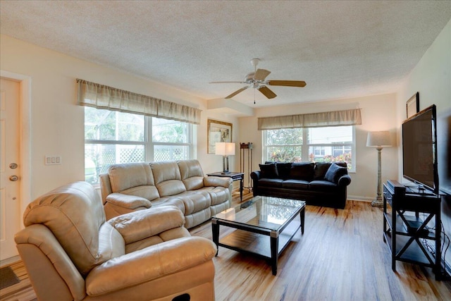 living area with ceiling fan, a textured ceiling, baseboards, and wood finished floors