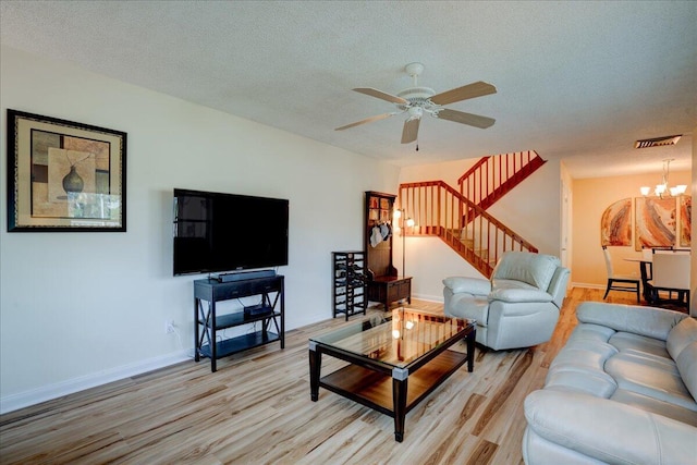 living room with light wood-type flooring, visible vents, stairway, and a textured ceiling