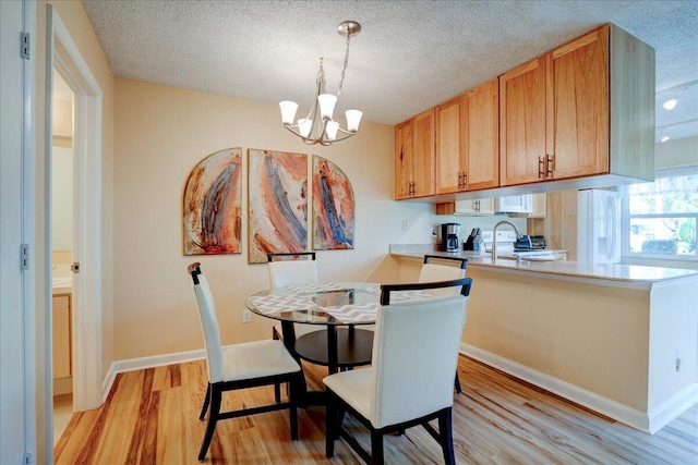 dining area with baseboards, light wood-style flooring, and a textured ceiling