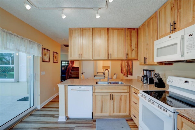 kitchen featuring white appliances, light countertops, a sink, and light brown cabinets