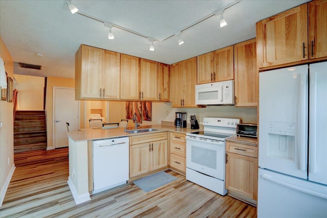 kitchen with white appliances, light wood-style flooring, a peninsula, light countertops, and a sink