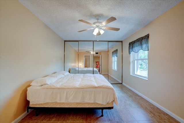 bedroom with a textured ceiling, a ceiling fan, and baseboards