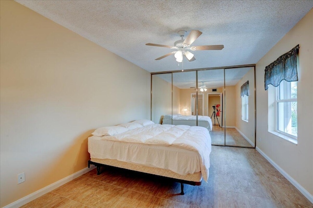 bedroom with a ceiling fan, a textured ceiling, and baseboards