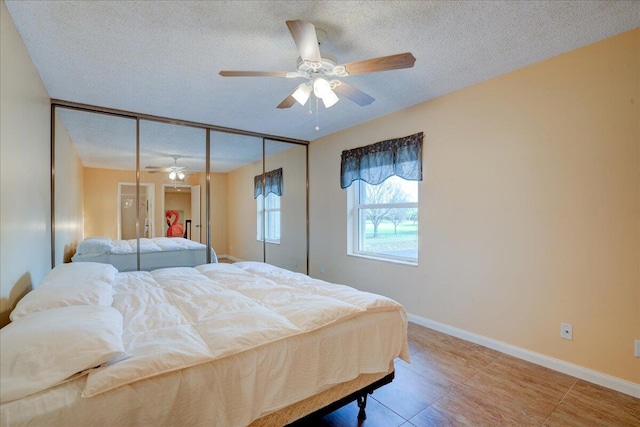 bedroom featuring ceiling fan, a closet, baseboards, and a textured ceiling