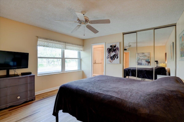 bedroom with a textured ceiling, ceiling fan, wood finished floors, baseboards, and a closet