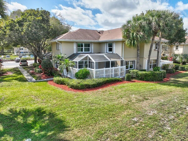 rear view of house featuring a lawn and a sunroom