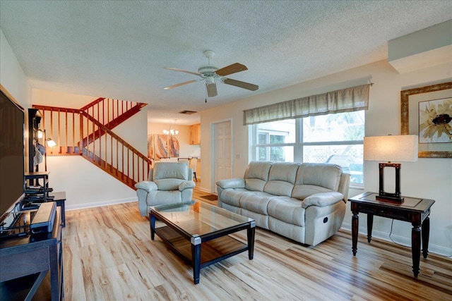 living room featuring light wood finished floors, visible vents, stairway, a textured ceiling, and baseboards