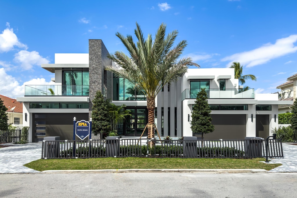 contemporary house with a fenced front yard, decorative driveway, and stucco siding