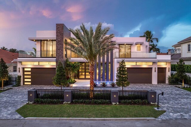 contemporary house with a fenced front yard, decorative driveway, and stucco siding