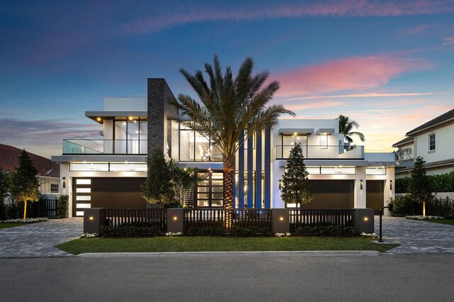 modern home with a garage, decorative driveway, fence, and stucco siding