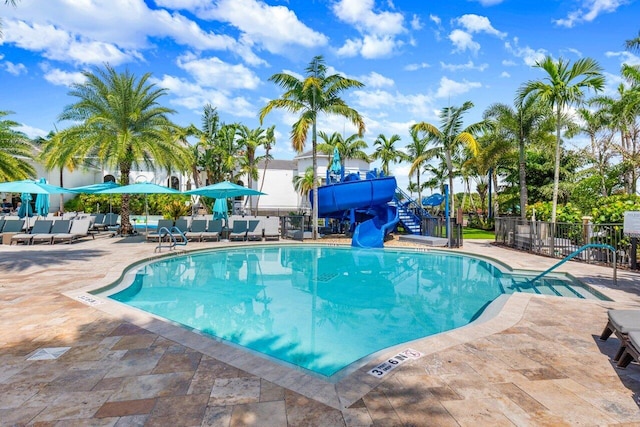 pool featuring fence, a water slide, and a patio