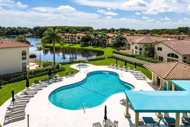 community pool with a patio, a lawn, a water view, and a fenced backyard