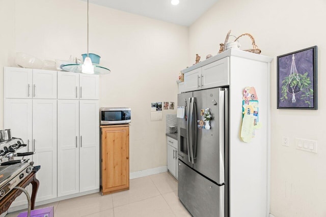 kitchen featuring stainless steel appliances, white cabinets, decorative light fixtures, and light tile patterned floors