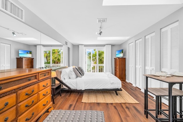 bedroom with dark wood-style floors, multiple windows, and visible vents