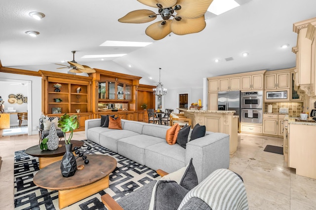 living area with ceiling fan with notable chandelier, lofted ceiling with skylight, and visible vents