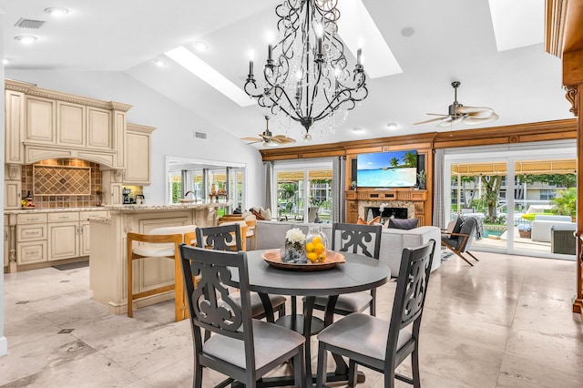 dining room with high vaulted ceiling, a skylight, a fireplace, and a ceiling fan