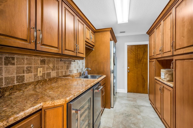 kitchen featuring light stone counters, wine cooler, brown cabinets, backsplash, and a sink