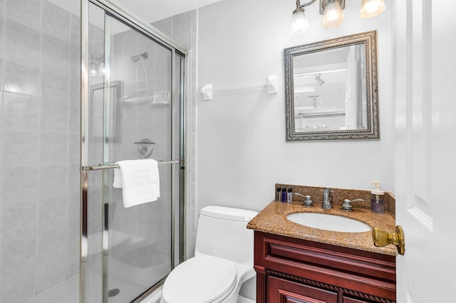 bathroom featuring vanity, a shower stall, and toilet