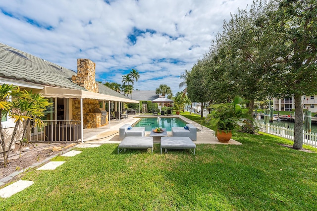 outdoor pool featuring a patio, outdoor dry bar, a water view, fence, and a yard