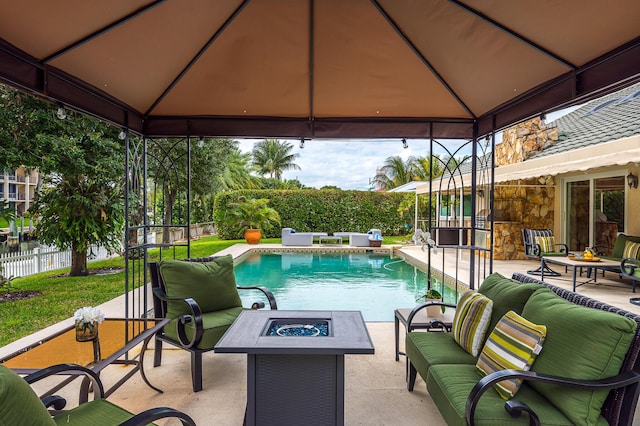 view of swimming pool with a gazebo, a patio area, fence private yard, and an outdoor living space with a fire pit