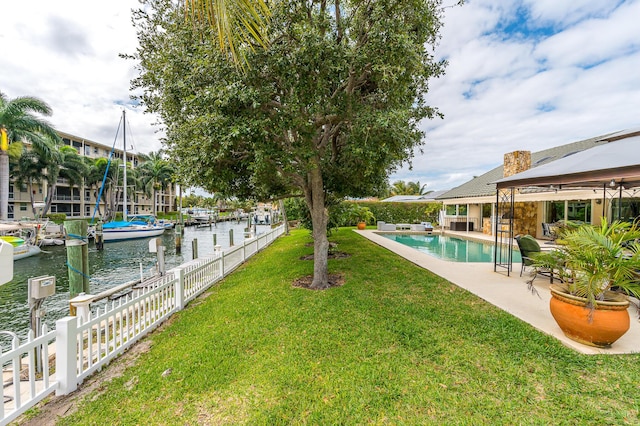 view of yard featuring a water view, a patio area, fence, and an outdoor pool