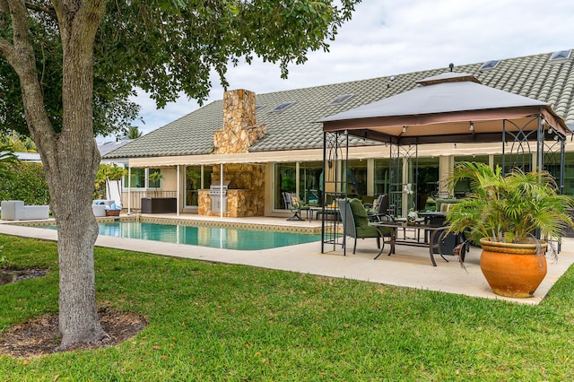 rear view of property with a tile roof, a gazebo, a yard, an outdoor pool, and a patio area