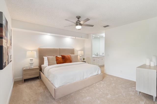 bedroom featuring light carpet, baseboards, visible vents, connected bathroom, and a textured ceiling