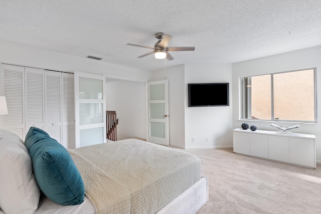 bedroom with light carpet, a textured ceiling, visible vents, and a closet