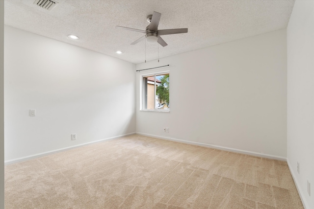 empty room featuring a textured ceiling, recessed lighting, light colored carpet, visible vents, and baseboards