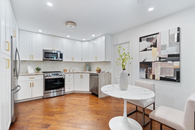 kitchen with a sink, backsplash, stainless steel appliances, and hardwood / wood-style floors