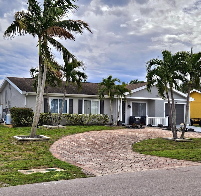 ranch-style home with a front yard, decorative driveway, an attached garage, and stucco siding