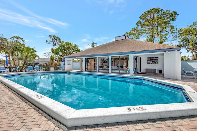 community pool featuring an outdoor structure, fence, and a patio